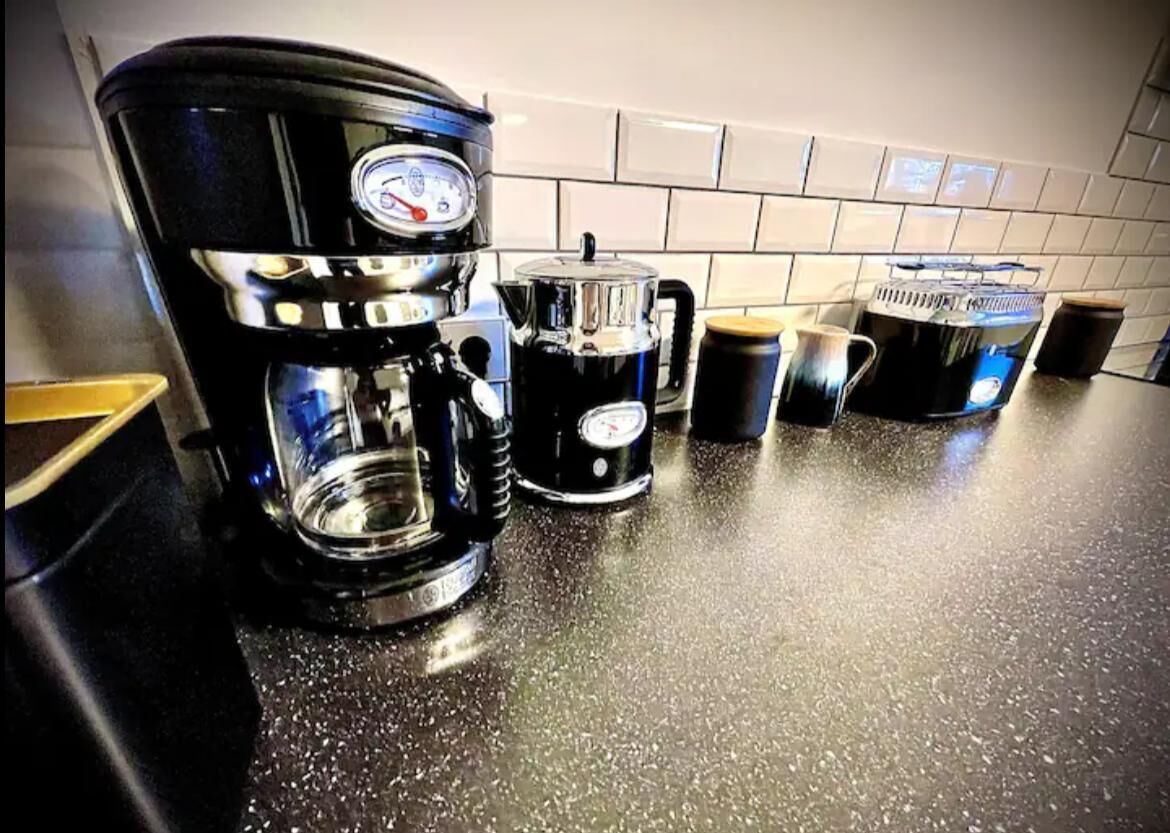 A kitchen counter with a coffee maker, a kettle, and a mug.