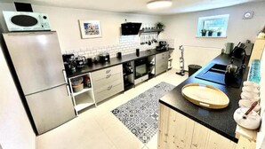 A modern kitchen with stainless steel appliances, a black countertop, and a patterned rug.