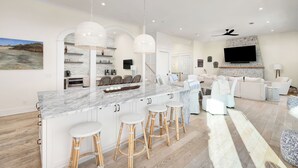 Una cocina moderna con una isla de mármol, taburetes de bar e iluminación colgante.