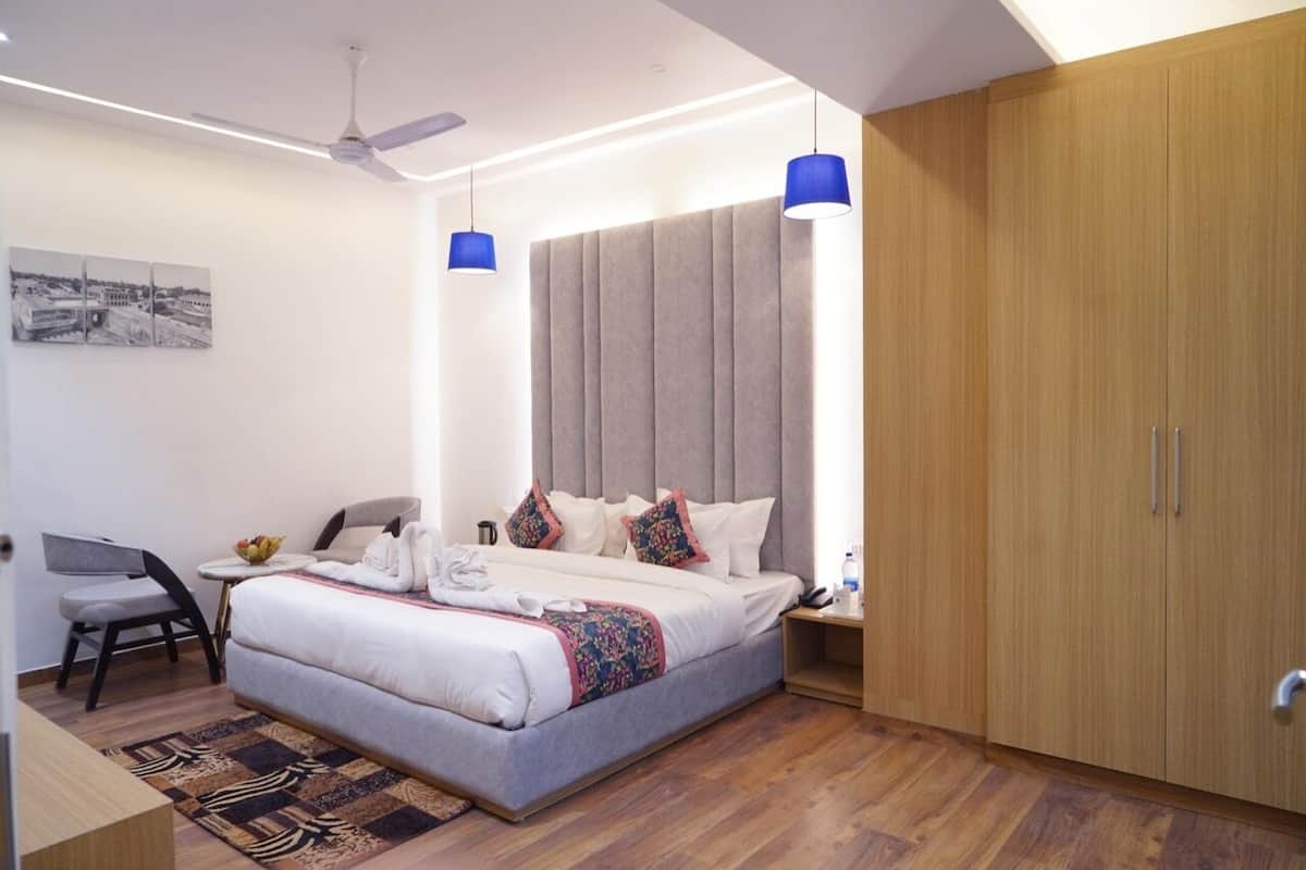 A modern hotel room with a large bed, a desk, and a wardrobe.