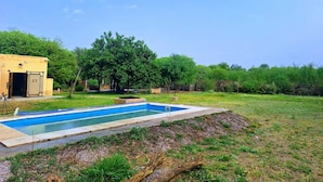 A swimming pool with a small building and trees in the background.
