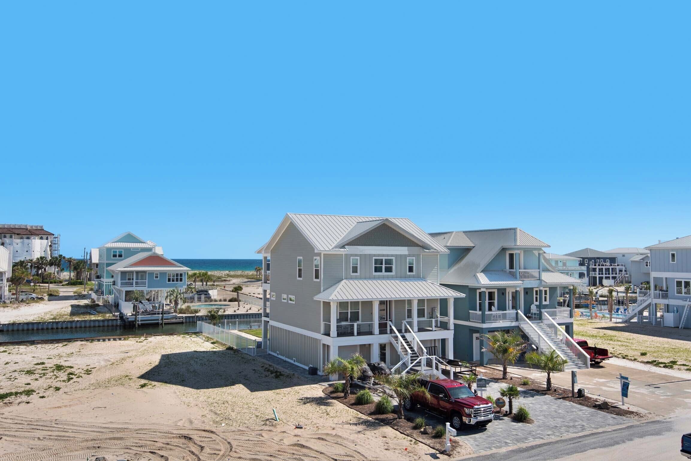A beachfront property with multiple houses, a dock, and a sandy beach.