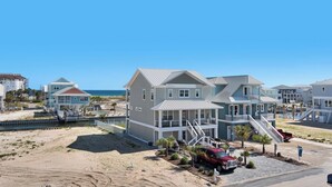 Une propriété située en bord de mer, comprenant plusieurs maisons, un quai et une plage de sable.