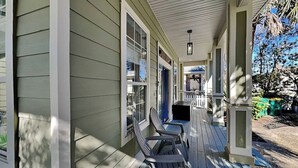 Une véranda abritée avec deux fauteuils Adirondack, une petite table et un banc.