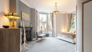 A bedroom with a bed, a desk, a chair, a fireplace, and a view of the outside. - Host & Stay | Chatsworth Townhouse I (Carlisle)