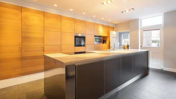 A modern kitchen with a central island, built-in ovens, and a large window providing natural light. - Host & Stay | Chatsworth Townhouse I (Carlisle)