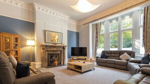 A living room with a fireplace, a television, and a sofa set. - Host & Stay | Chatsworth Townhouse I (Carlisle)