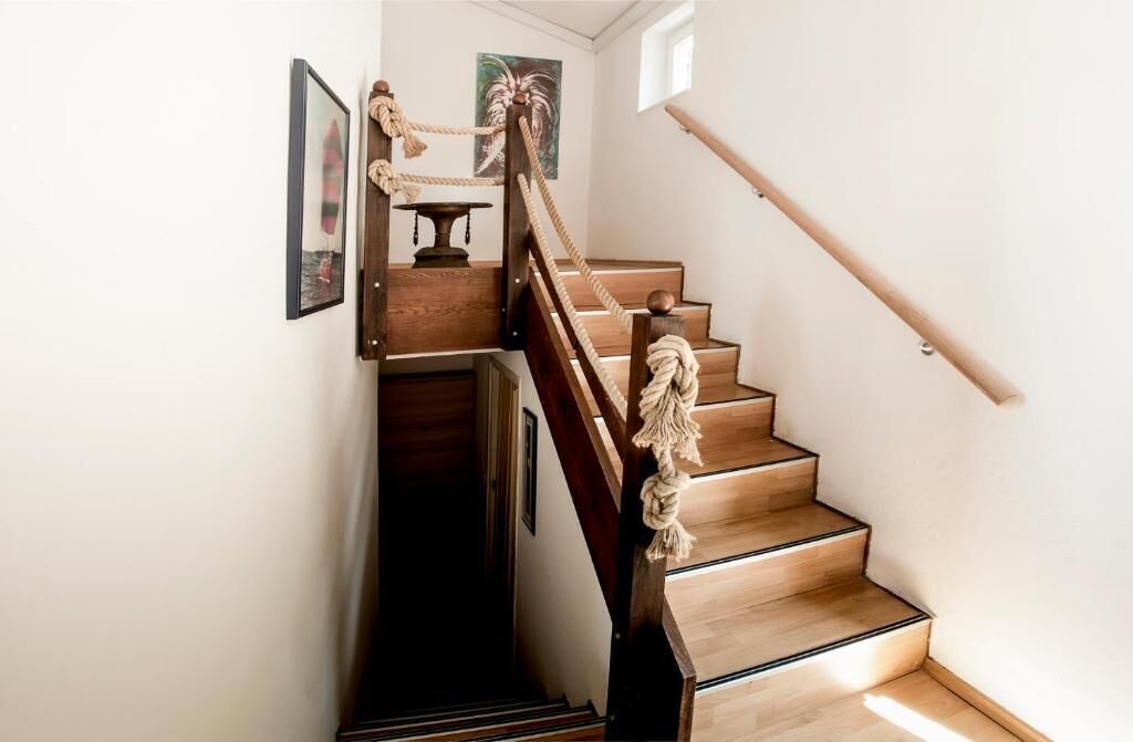 A wooden staircase with a rope handrail and a wooden banister.