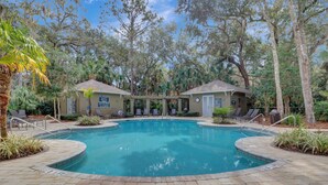 A swimming pool with a circular design, surrounded by lounge chairs and covered seating areas. - Beautiful villa w/ nature views & screened porch only minutes from the beach (Hilton Head Island)