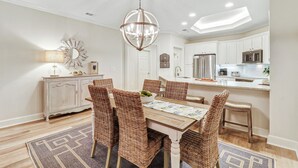 A dining area with a round table, wicker chairs, and a chandelier.