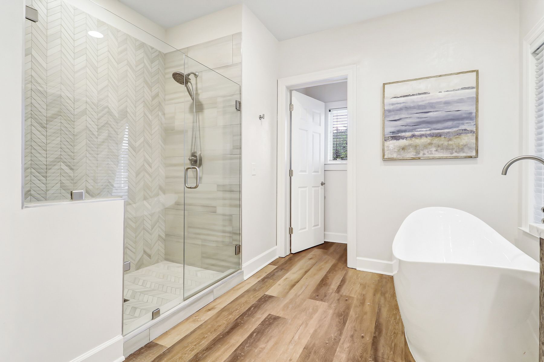 A modern bathroom with a glass-enclosed shower, a freestanding bathtub, and a wooden floor.