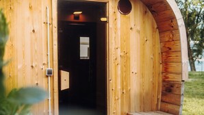 Una estructura de madera circular con una puerta, un banco pequeño y un escalón que lleva a la entrada.