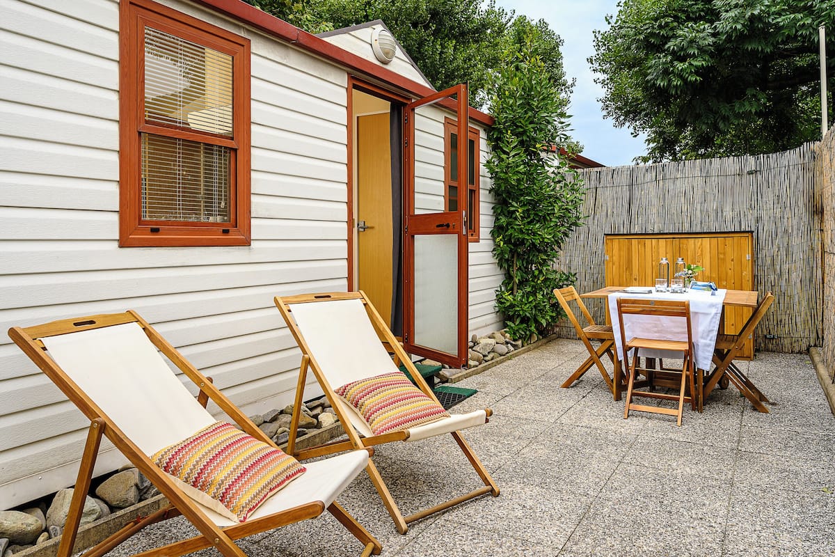 Une petite maison avec deux chaises à ossature en bois et une table recouverte d’une nappe blanche.