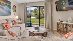 A modern living room with a sofa, coffee table, and a TV mounted on the wall. - Crystal Cove 28A-Walk to Beach-Sleeps 6 (Miramar Beach)