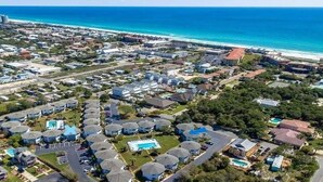 An aerial view of a coastal residential area with houses, a swimming pool, and a beach in the background. - Crystal Cove 28A-Walk to Beach-Sleeps 6 (Miramar Beach)