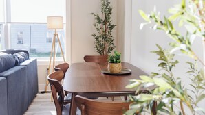 A dining area with a wooden table, chairs, a lamp, and a potted plant.