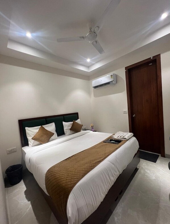 Une chambre d’hôtel équipée d’un lit, d’un ventilateur de plafond, d’un appareil de climatisation et d’une porte en bois.