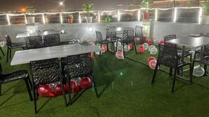 An outdoor dining area with tables and chairs, surrounded by potted plants and balloons. - HOTEL IVORY INN (New Delhi)