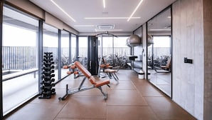 Une salle de sport moderne, équipée de matériel d’exercice, dotée de grandes fenêtres et offrant une vue sur l’extérieur.