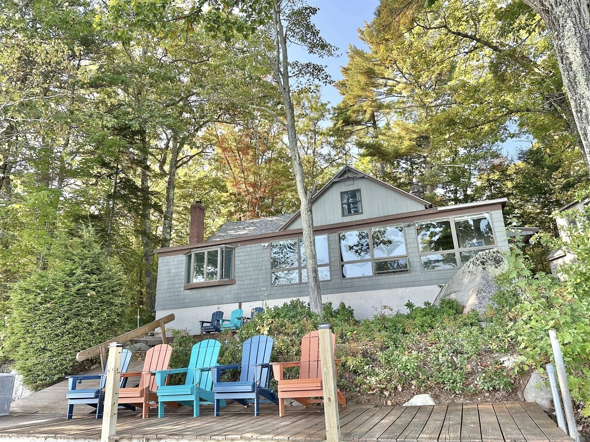 A two-story house with a deck, surrounded by trees.