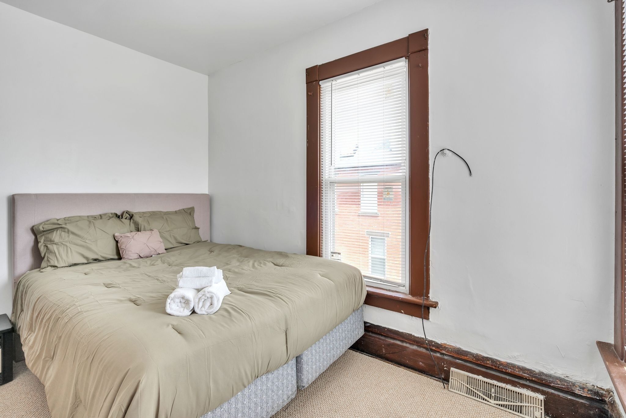 A bedroom with a bed, a window, and a radiator.