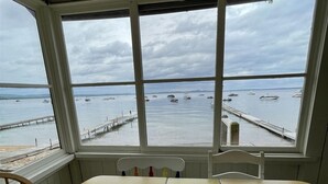Habitación con un amplio ventanal que da a una masa de agua con barcos y un muelle.