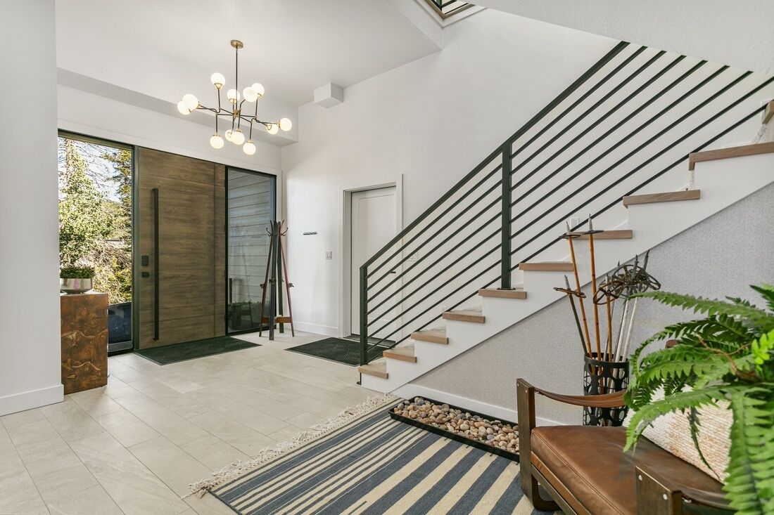 A modern interior with a staircase, a large window, and a chandelier.