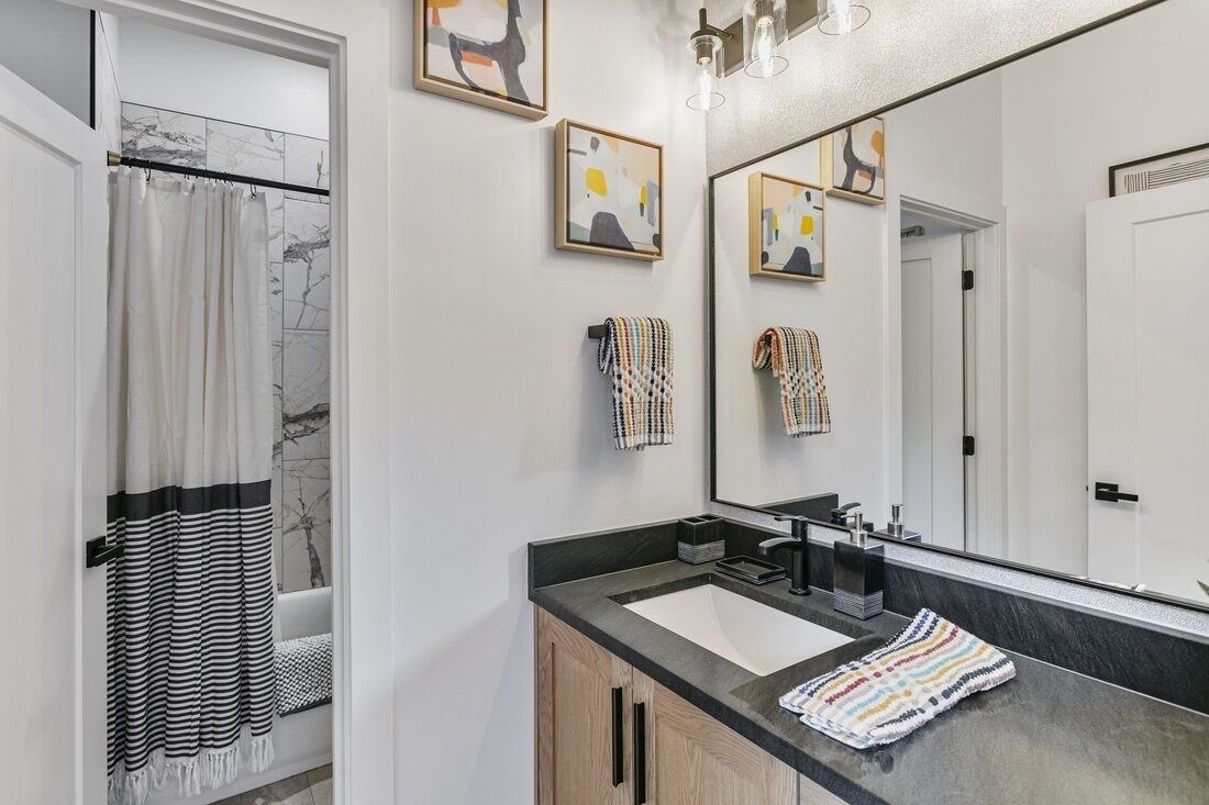 Une salle de bain moderne avec un grand miroir, deux lavabos et un espace douche.