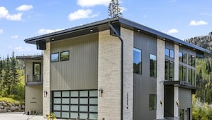 Een modern herenhuis met garage, gevel van natuursteen en grote ramen.
