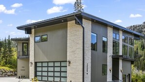Een modern herenhuis met garage, gevel van natuursteen en grote ramen.