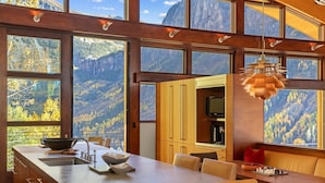 Eine moderne Küche mit großen Fenstern, einem Essbereich und Bergblick.