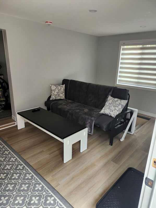 A modern living room with a black sofa, white coffee table, and patterned rug.