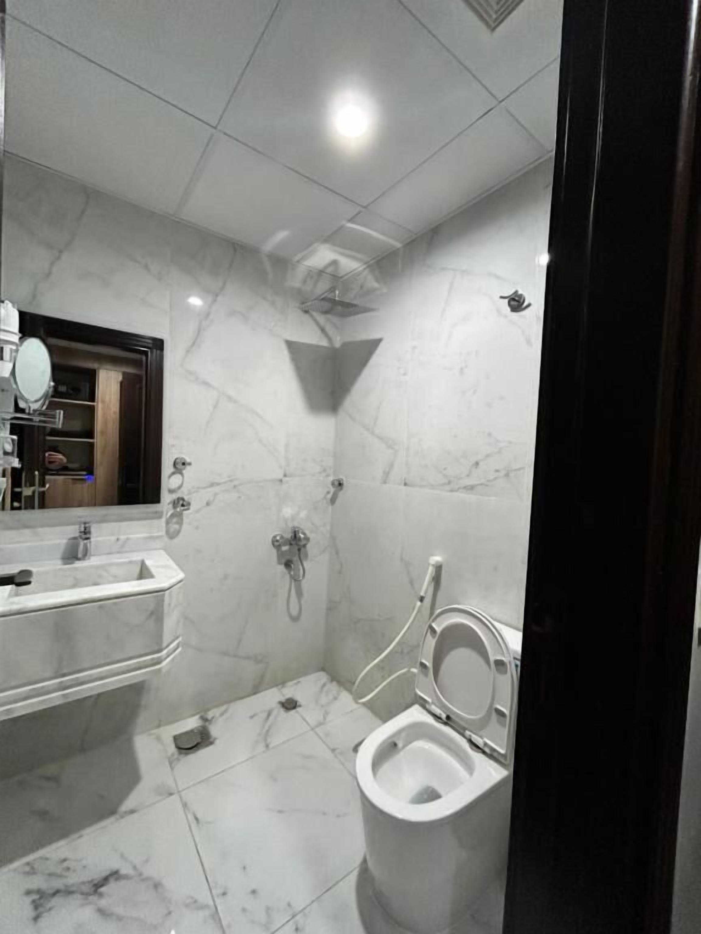A bathroom with a marble floor, a sink, a mirror, and a toilet.