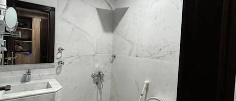 A bathroom with a marble floor, a sink, a mirror, and a toilet.