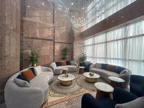 A spacious lounge area with a high ceiling, marble walls, and large windows. - Blue Pearl Hotel (Makkah)