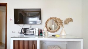 A modern room with a flat-screen TV mounted on the wall, a microwave, a kettle, and a small table with a vase of dried pampas grass. - Cleopatra Pyramids Elite (Giza)