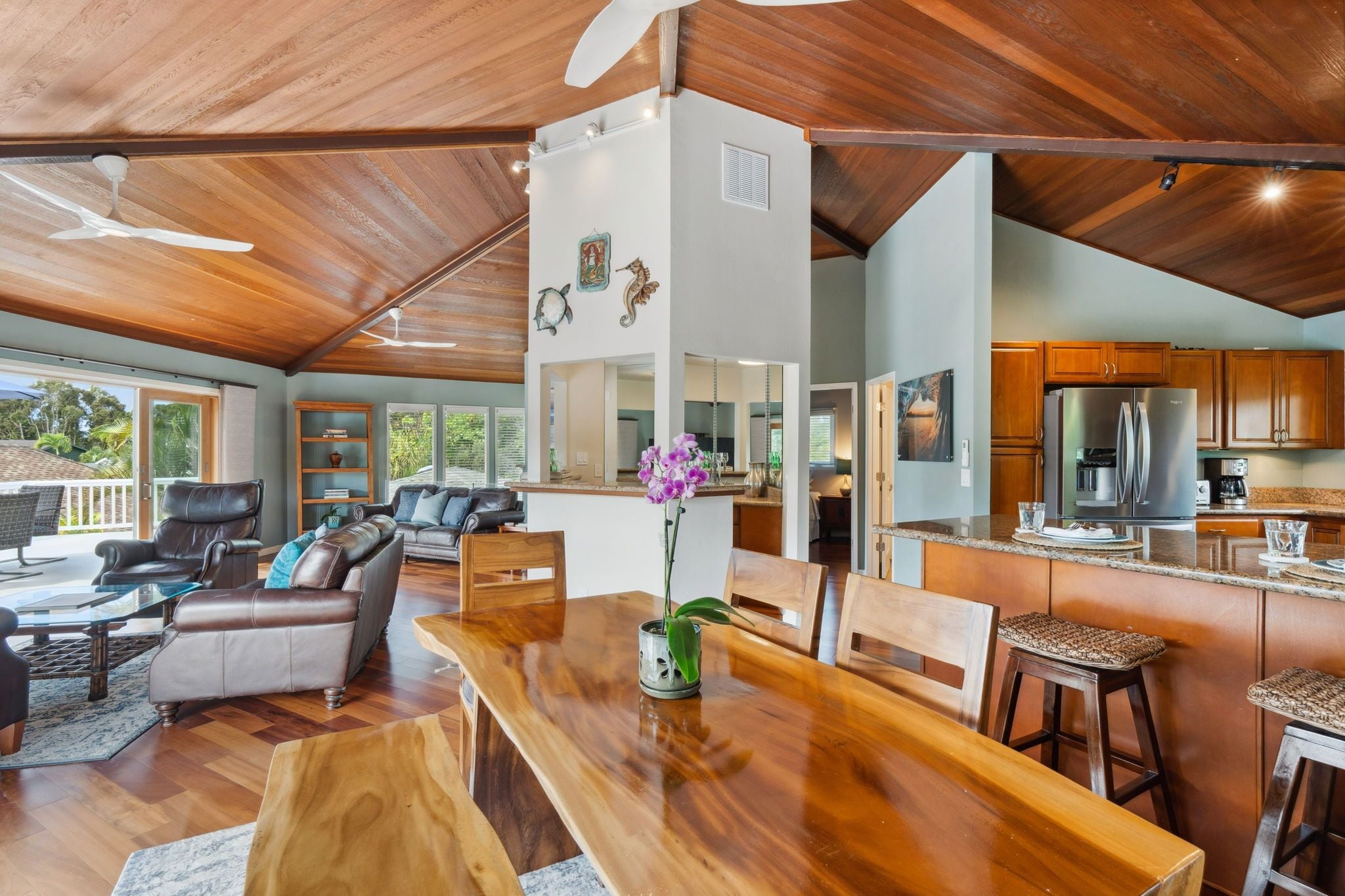 A spacious living area with a wooden ceiling, a dining table, and a kitchen with wooden cabinets.