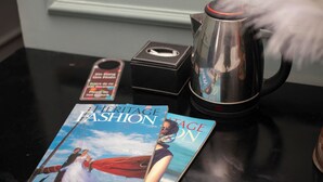 Una revista titulada 'Heritage Fashion' sobre una mesa, una caja negra y un hervidor de acero inoxidable.