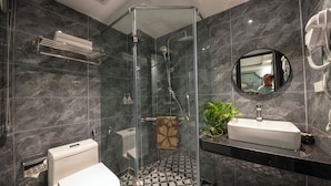 Un baño moderno con ducha envuelta en vidrio, inodoro, lavamanos con espejo y toallero.