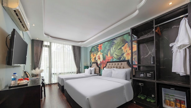Habitación de hotel con dos camas, televisión de pantalla plana, minibar y zona de ducha.