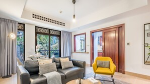 Ett modernt vardagsrum med en svart lädersoffa, en gul fåtölj och ett runt soffbord.