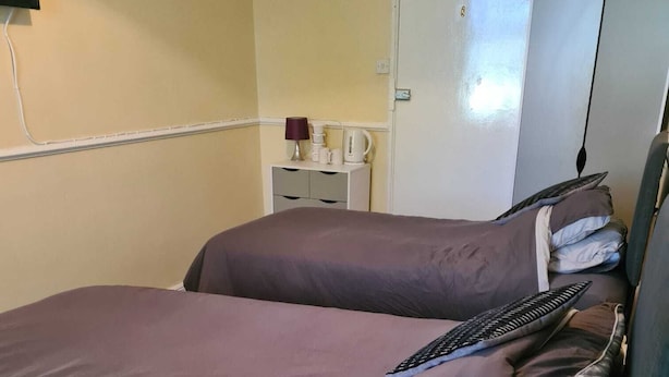 A hotel room with two beds, a desk, a wardrobe, and a television. - The Eagle and child  (Preston)