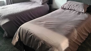 A hotel room with two single beds, a dark headboard, and a window with curtains. - The Eagle and child  (Preston)