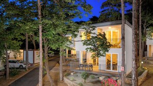 A two-story house with a balcony, surrounded by trees and a stone pathway. - Holiday Homes Oštro (Kraljevica)