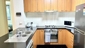 Una cocina moderna con electrodomésticos de acero inoxidable, armarios de madera y encimera negra.