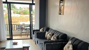 Un salon moderne avec un canapé d’angle, une table à manger et une vue sur l’extérieur, accessible par une porte vitrée.