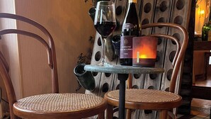 Un tavolo con una bottiglia di Domaine 2015 Bourbon, un bicchiere di vino rosso e una candela.