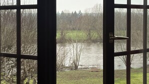 Una vista attraverso una finestra che mostra un fiume, alberi e una zona erbosa.