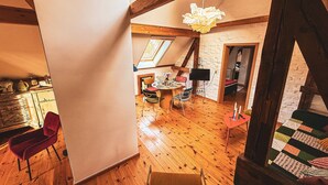 A loft-style room with wooden beams, a sloped ceiling, and a skylight.