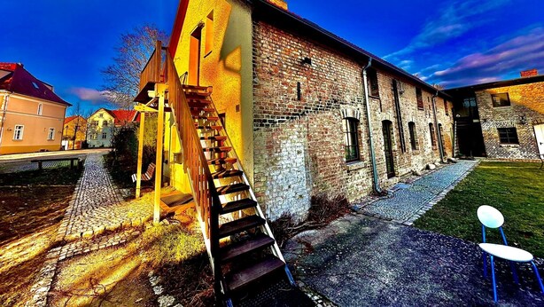 A historic building with a brick facade, a wooden staircase, and a cobblestone pathway.
